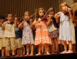 kids playing violin on stage